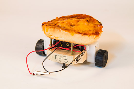 A homemade robot with a pizza slice for a body, mounted on toy wheels